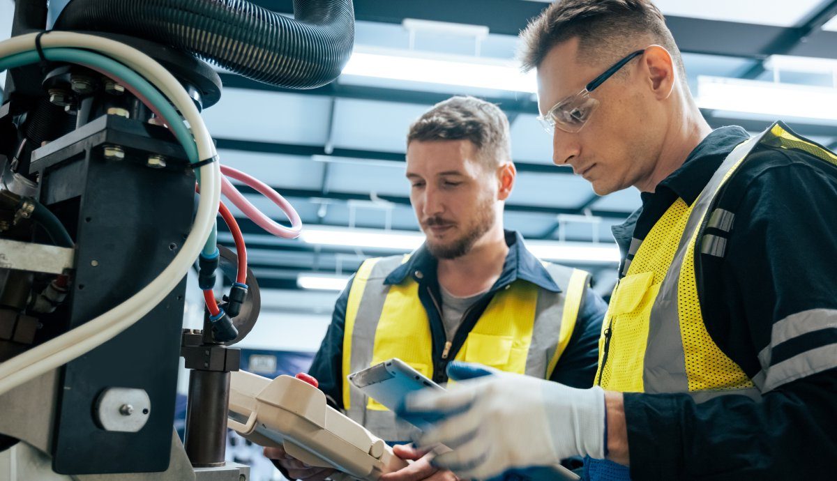 Kurzfristigen Personalbedarf: Zwei Mitarbeiter arbeiten gemeinsam an einer Produktionsmaschine.